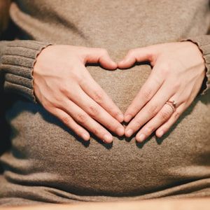 Hands forming a heart shape on a pregnant belly