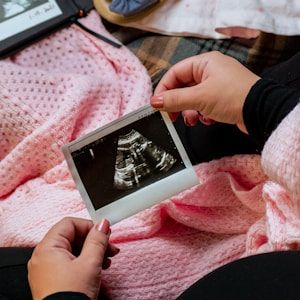 Mum holding baby's first scan on a pink blanket